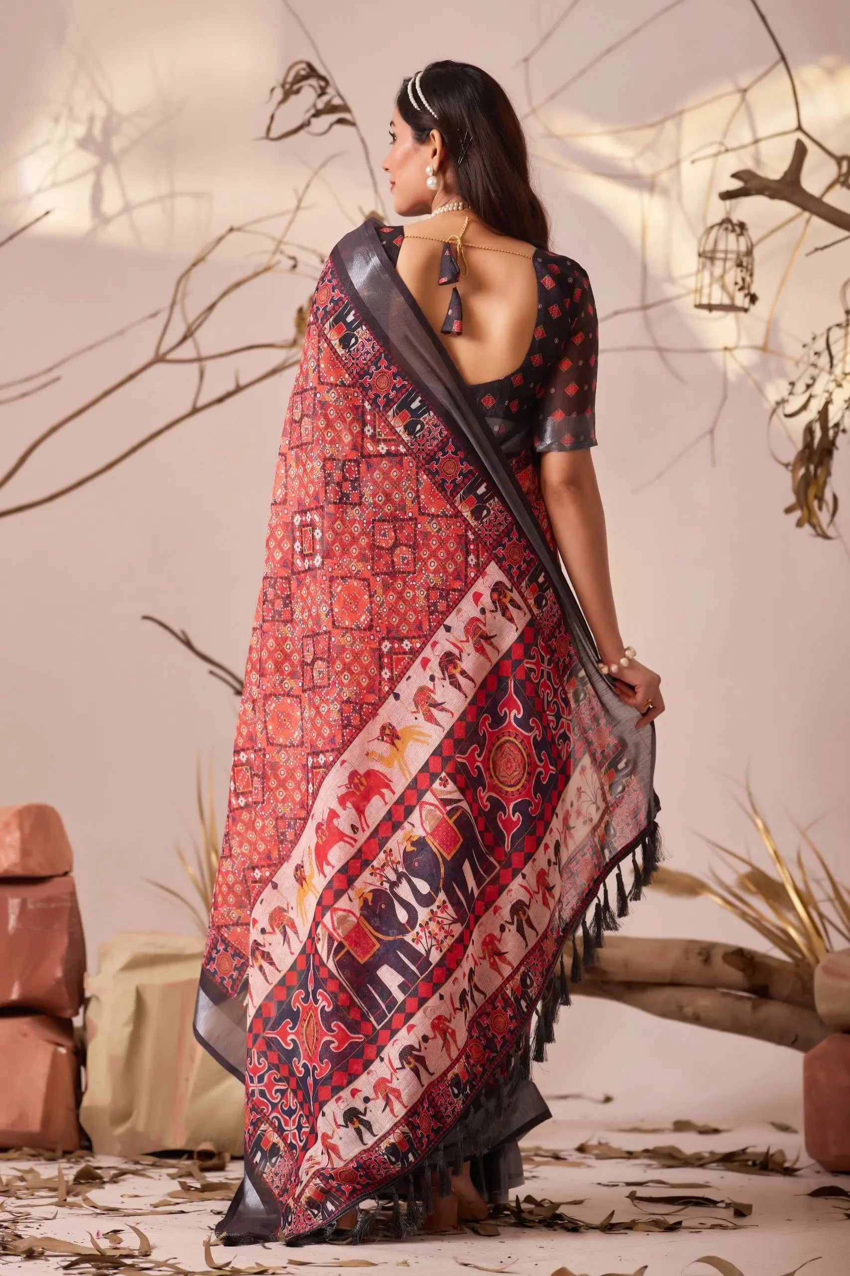 Woman wearing a traditional saree with intricate patterns in a decorative setting.